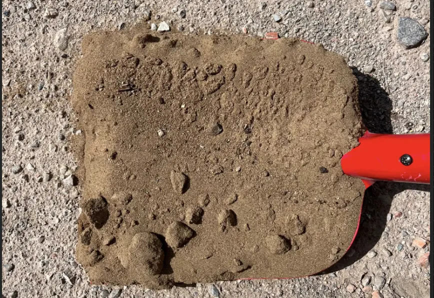 Füllsand und Natursand als Materialprobe auf roter Schaufel