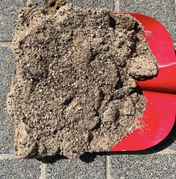 Gewaschener Wesersand 0/2 als Materialprobe auf roter Schaufel