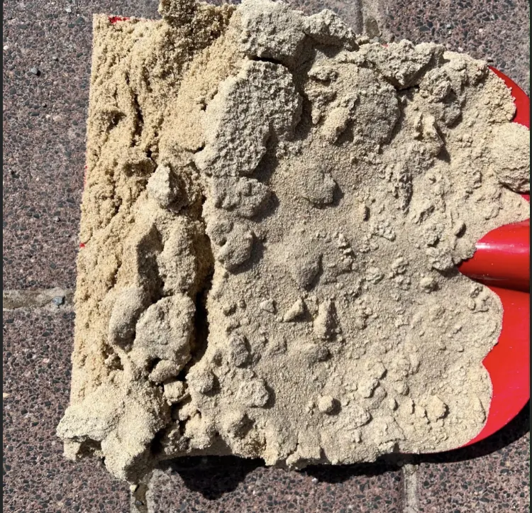 Spielsand und Fallschutzsand als Materialprobe auf roter Schaufel